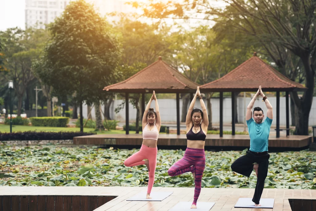 3 People practicisng yoga by the beachfront resort in candolim goa